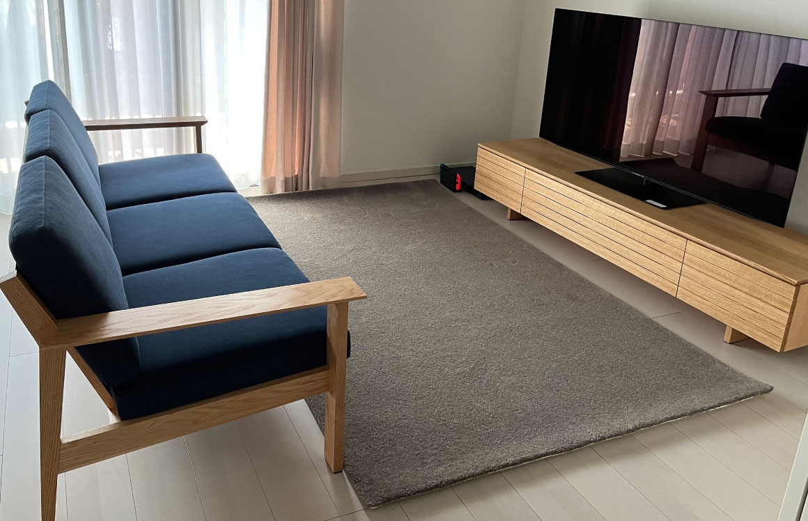 白い床にテレビボードとソファはオーク材でまとめ、帆布のネイビーブルーがさわやかなアクセントになっているリビングコーディネート。